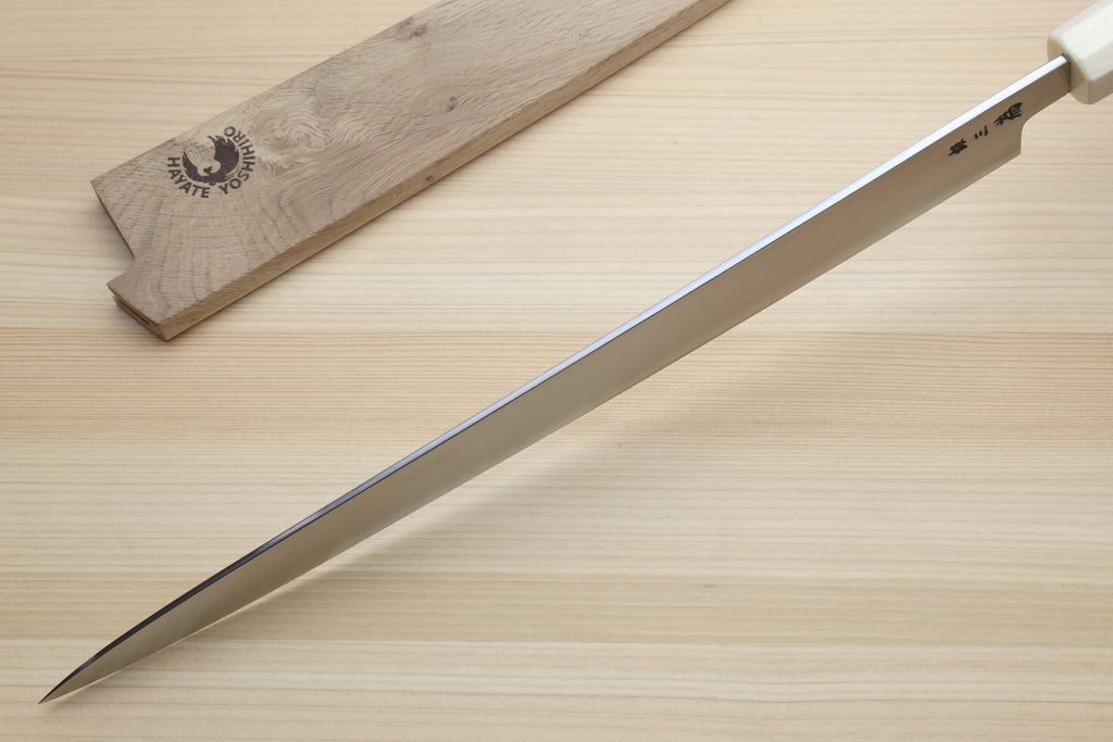 A Japanese-style honing steel with a silver blade and cream handle, shown diagonally on a light wood surface next to its wooden storage case. The case features a black logo for 'Daichi Shapite Tools'.