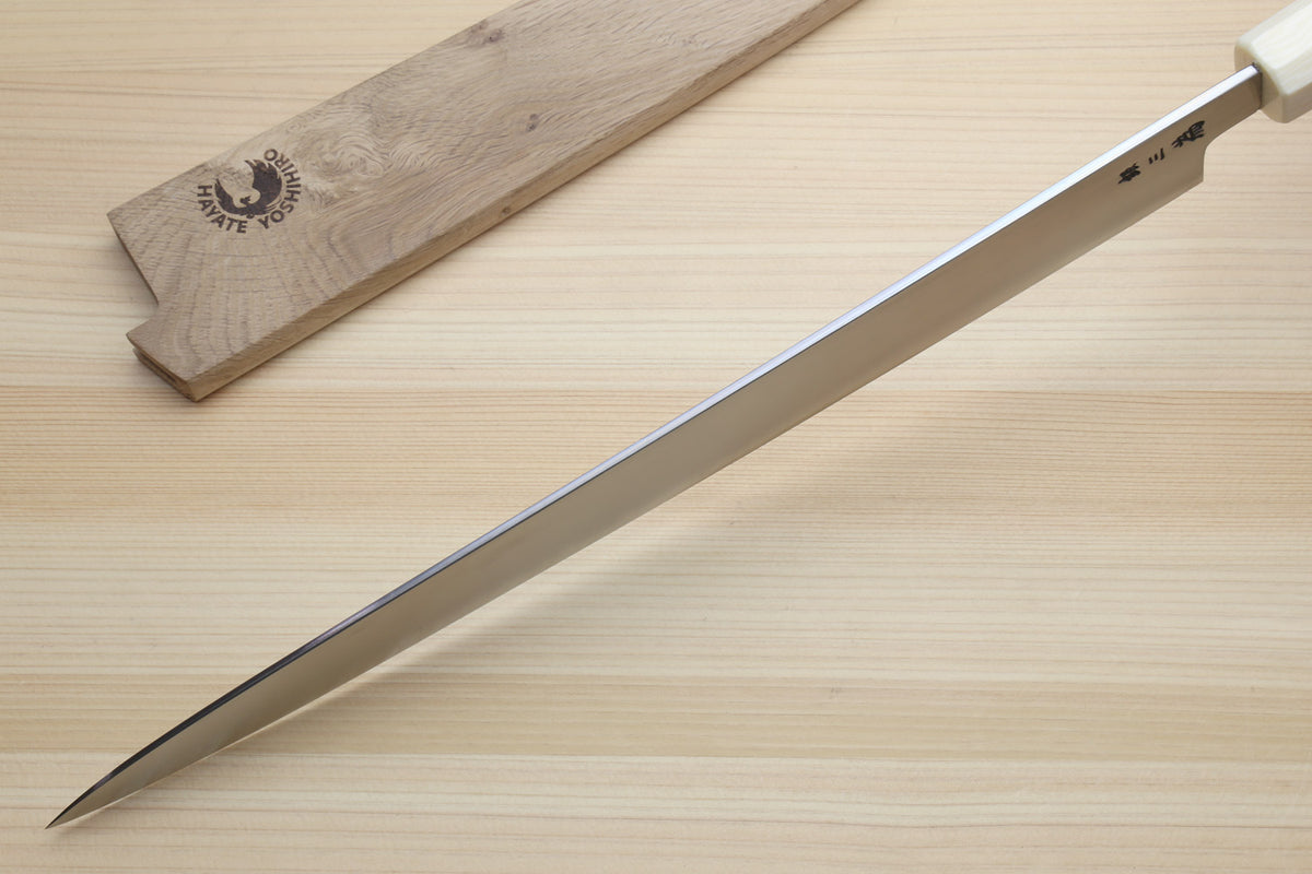 A Japanese-style honing steel with a silver blade and cream handle, shown diagonally on a light wood surface next to its wooden storage case. The case features a black logo for 'Daichi Shapite Tools'.