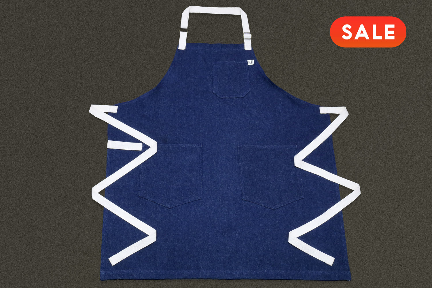 Blue denim apron on a dark background, featuring a 'SALE' label.