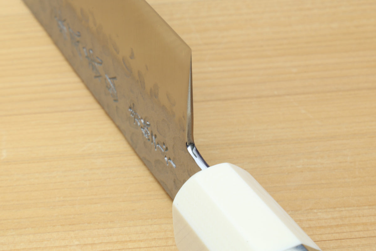 Gyuto chef knife heel and bolster detail with etched steel and white handle