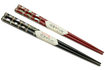 Pair of chopsticks with red and black lacquered finish, patterned caps