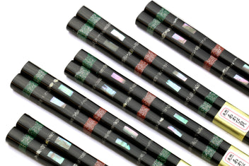 Five black chopsticks with green and red mosaic bands along the center
