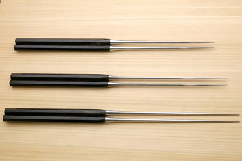 Set of three plating tweezers with ebony handles and stainless metal tips on wood
