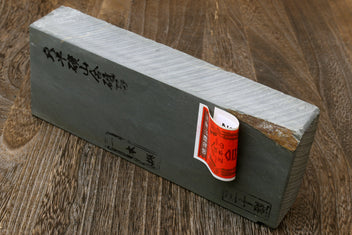 Light gray sharpening whetstone block with red-orange label on dark end