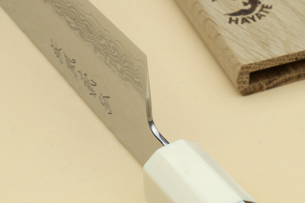 Close-up of Damascus blade edge and ivory-look handle with stamped markings