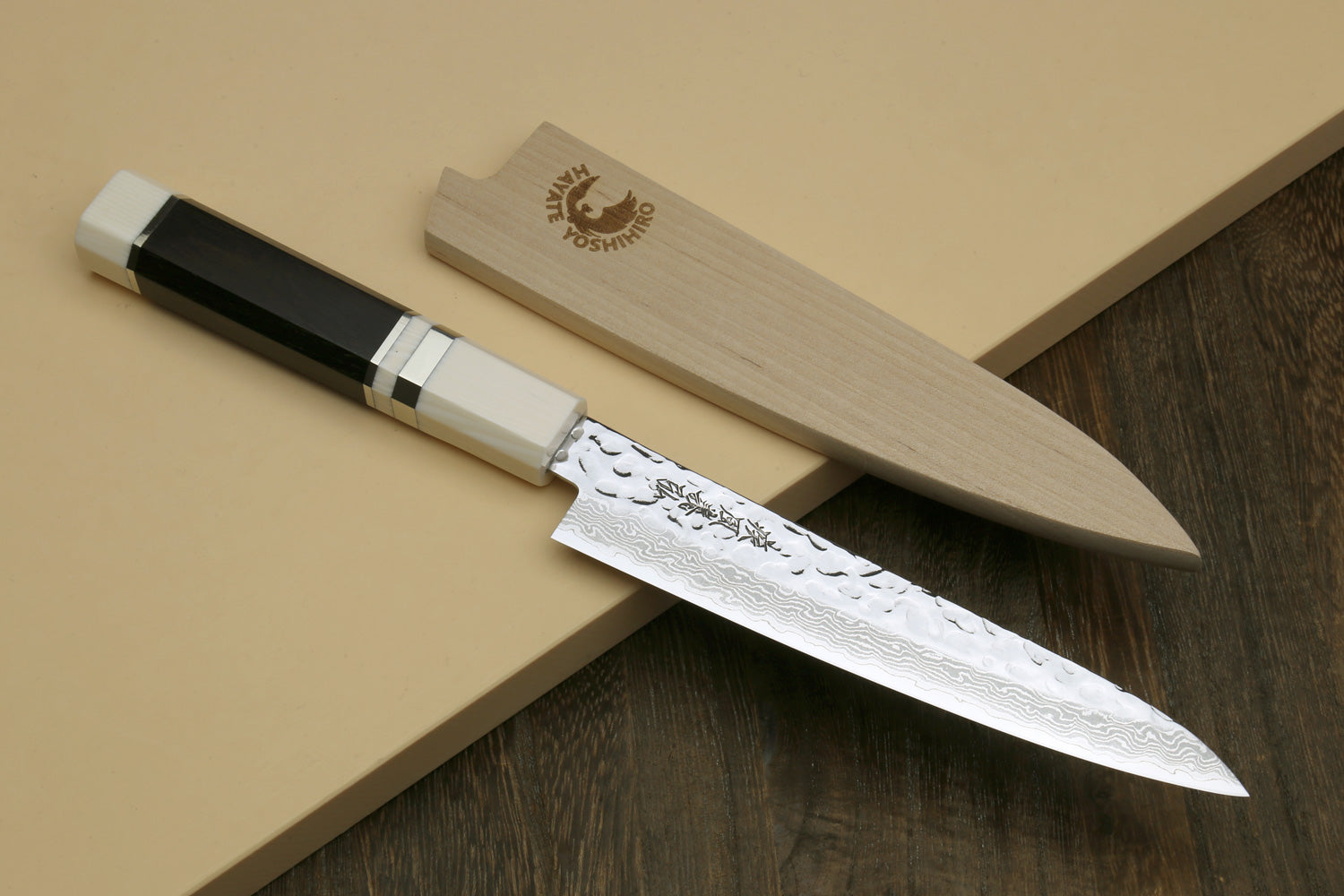 Two Damascus knives on wood display blocks with ivory-look octagonal handles