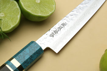 Damascus blade close-up with etched marks and turquoise blue handle.
