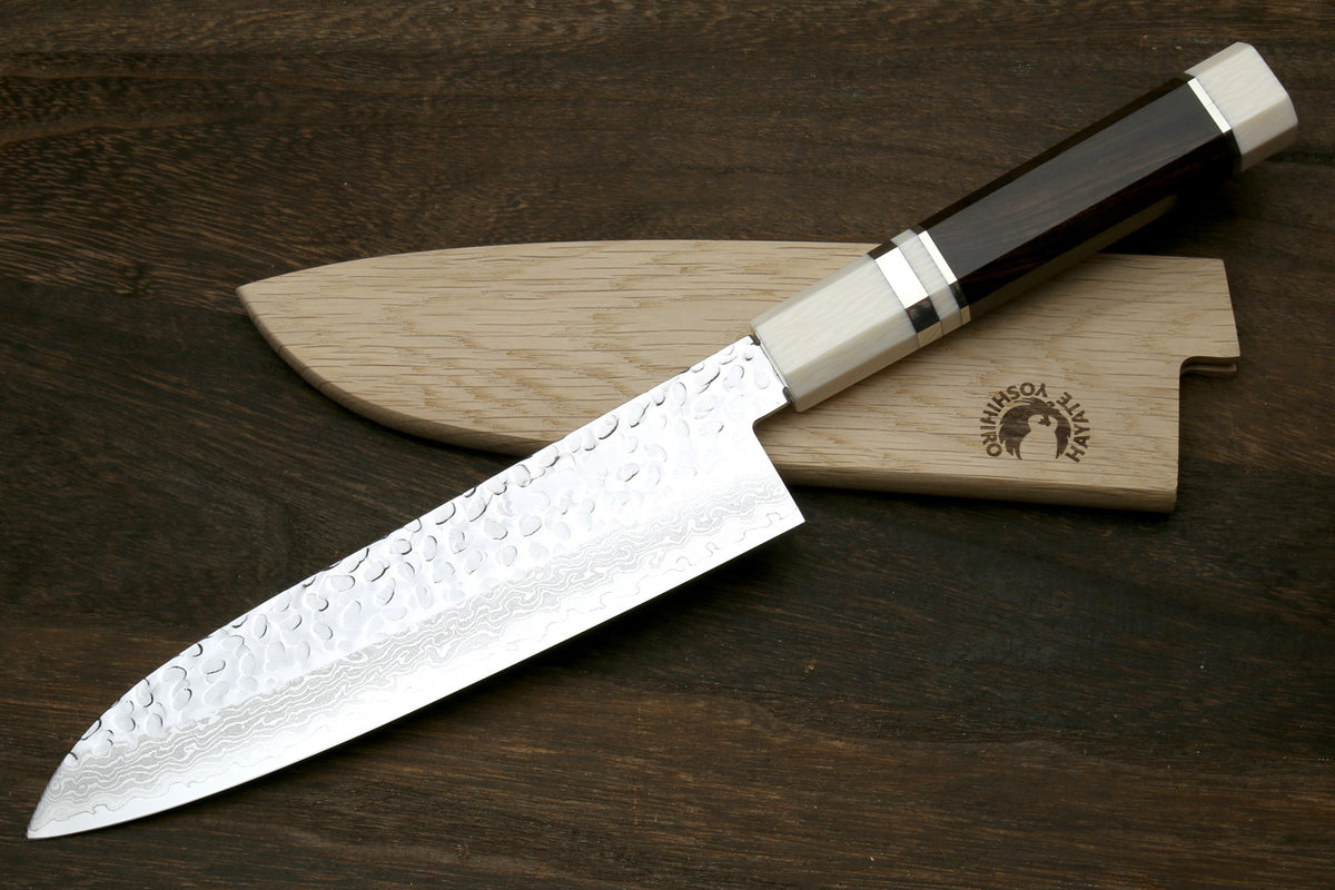 Damascus hammered Santoku knife with dark blade and light octagonal ivory-style handle.