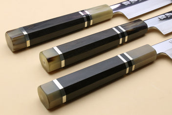 Two yanagi sashimi knives with dark triple-ring ebony handles and mirror-polished blades