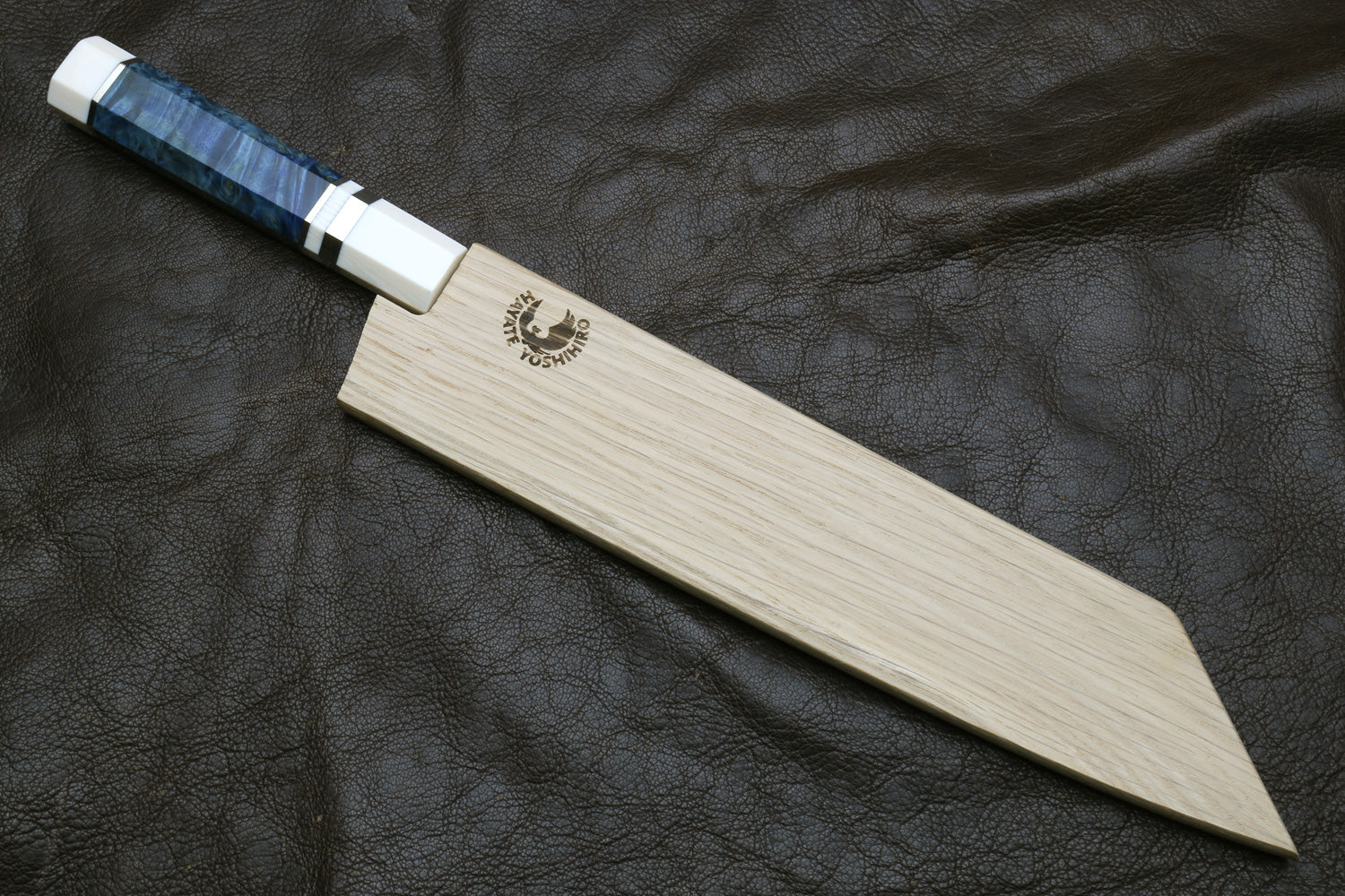 knife with a blue handle stored in a wooden sheath on a dark textured surface