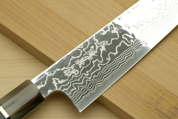 Damascus chef knife blade close-up with wavy pattern and part of blue octagonal handle