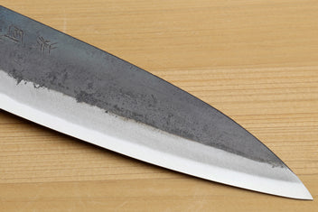 Petty utility knife blade close-up with kurouchi texture and sharpened edge