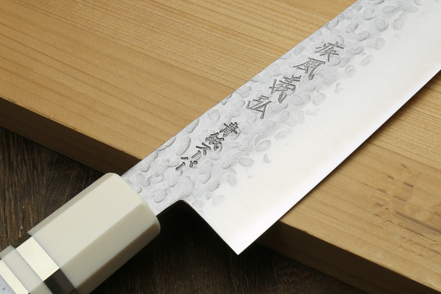 Knife with a white handle and blade featuring engraved text on a brown background