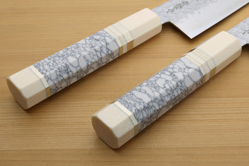 Chef's gyuto knife handles with white and gray crackle-pattern scales and bolster