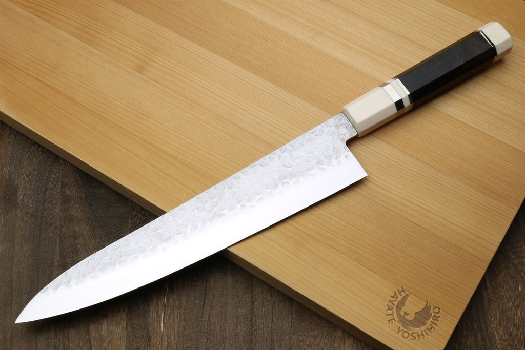 Backside of a Chef's knife with ebony handle on a wooden cutting board