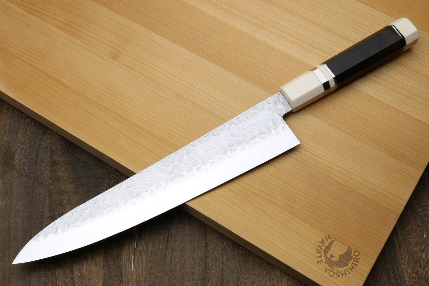 Backside of a Chef's knife with ebony handle on a wooden cutting board