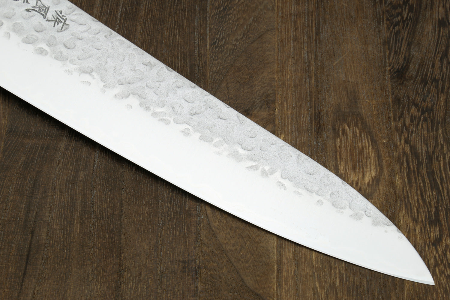 Close-up of a chef's knife blade on a wooden surface