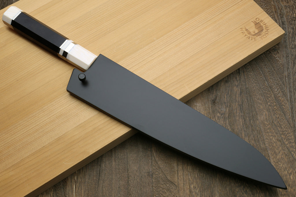 Chef's knife with a black sheath on a wooden cutting board