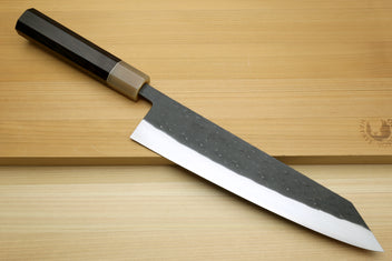 Kiritsuke chef knife with dark handle and textured black blade, silver cutting edge