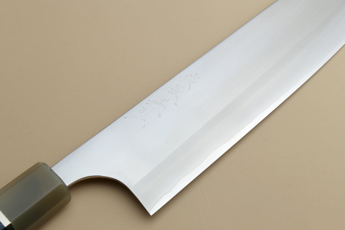 Gyuto chef's knife blade close-up with polished steel and etched signature