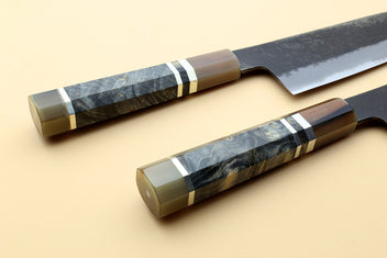 Santoku knives with patterned dark handles and blue-steel blades, side-by-side