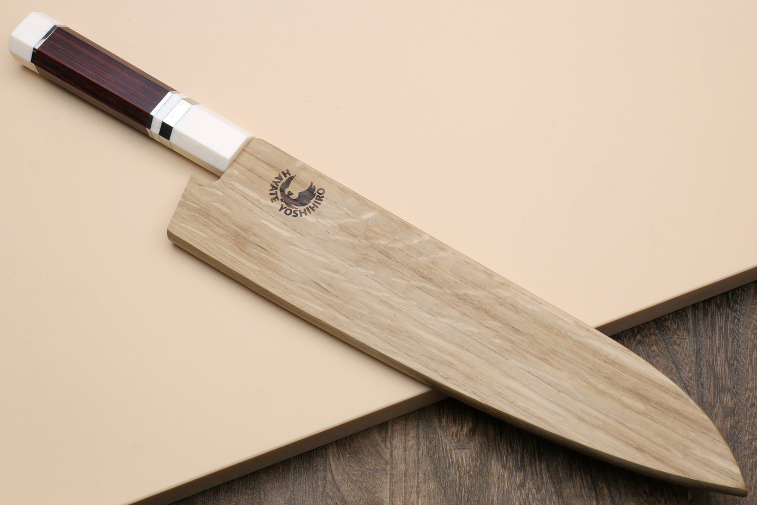 A Japanese-style chef's knife with a light wood-grain blade and a dark reddish-brown wooden handle, resting diagonally on a beige background.