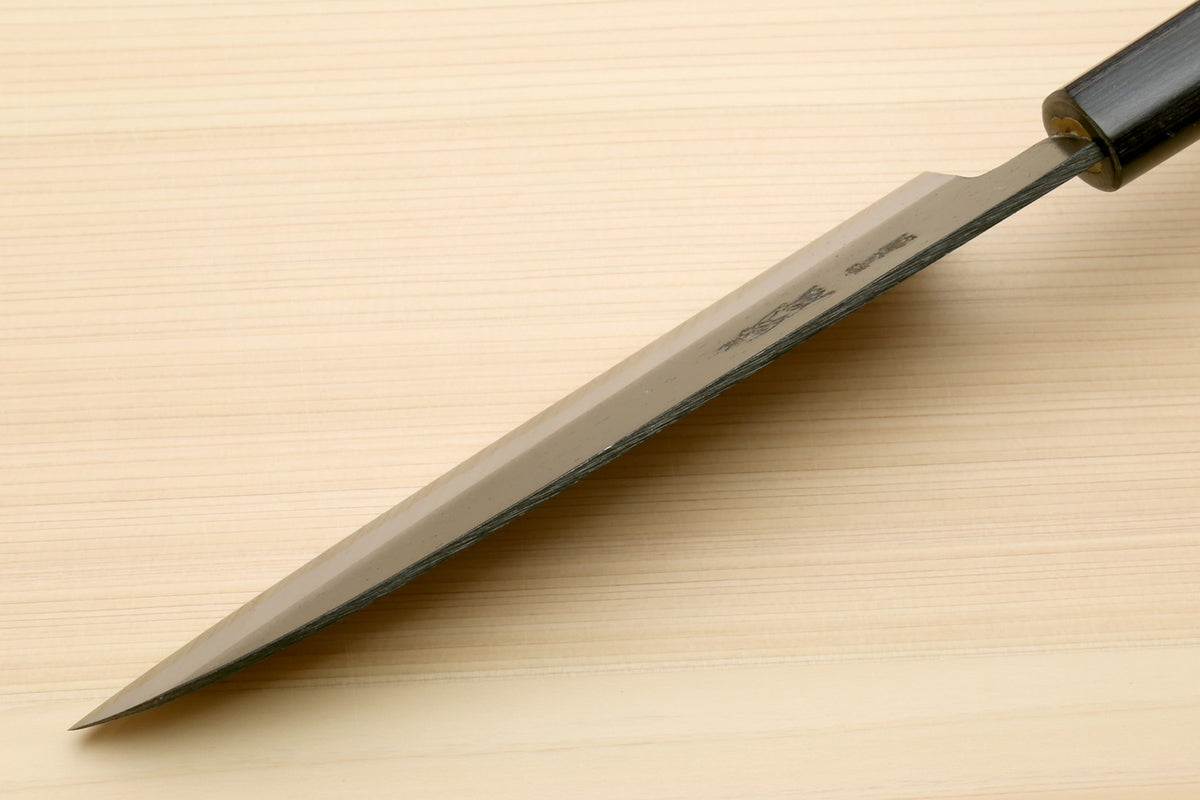 Chef knife with blackened blue steel blade and dark D-shaped handle, tip view