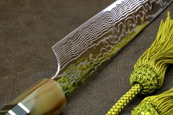 Sujihiki slicer knife blade close-up with damascus lines and gold-toned handle collar