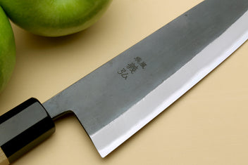 Santoku knife blade close-up with stamped markings and black bolster