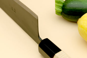 Gyuto chef knife heel close-up with pale camphor handle and black ferrule