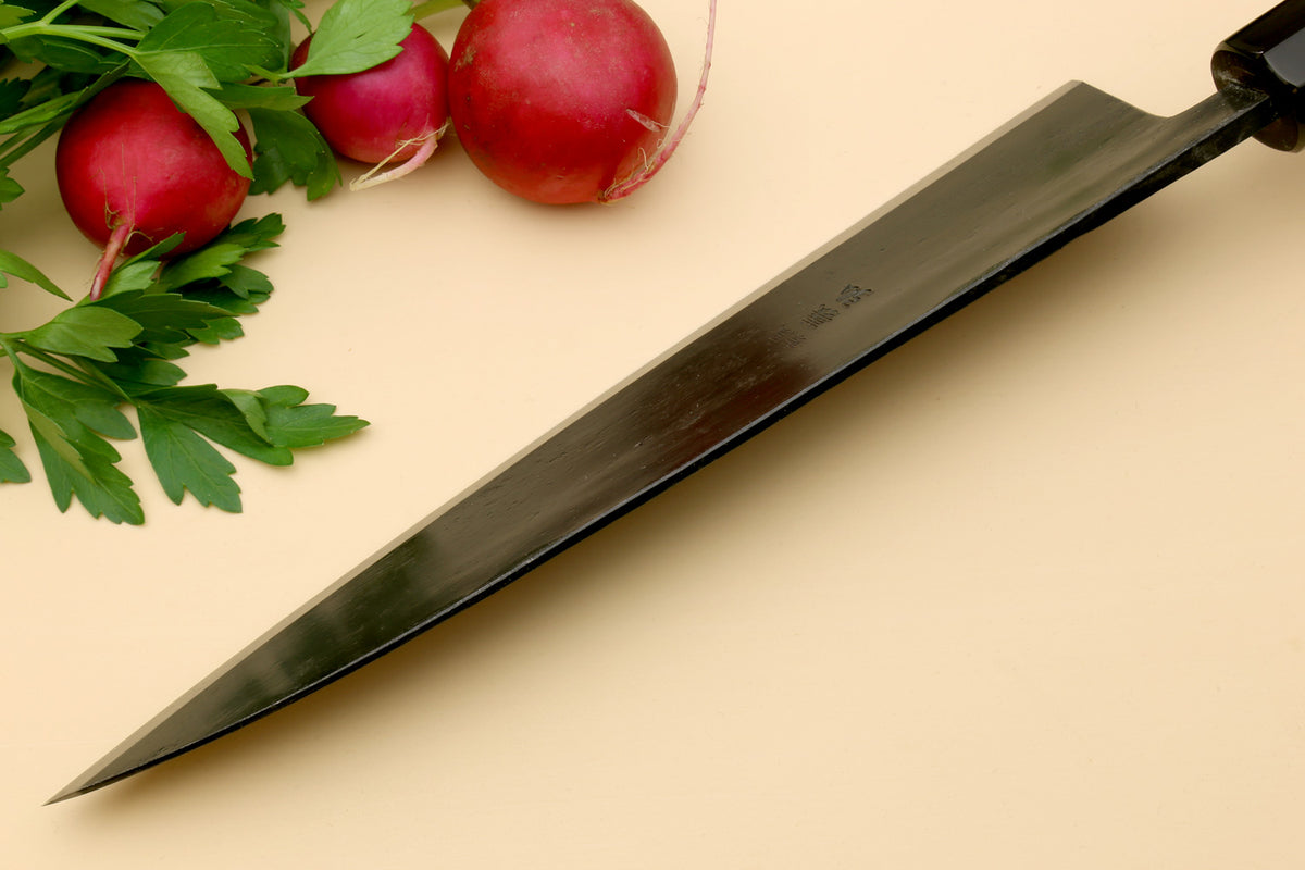 Gyuto chef knife side view with dark blade and pale camphor wood handle