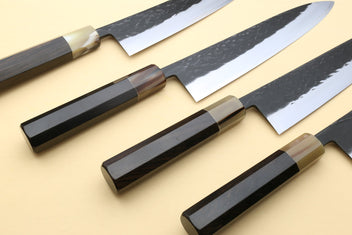 Three Gyuto chef's knives with dark handles and black-speckled blades