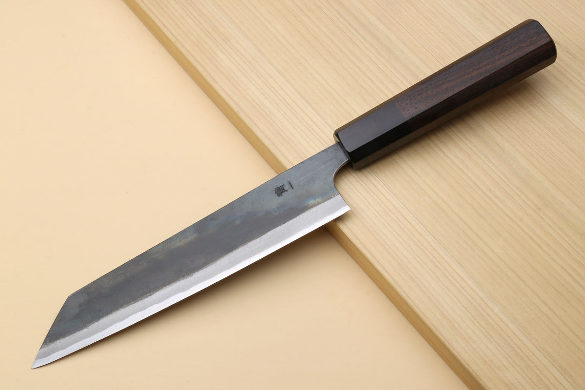 Japanese utility kiritsuke knife with dark handle and partially visible edge on steel blade