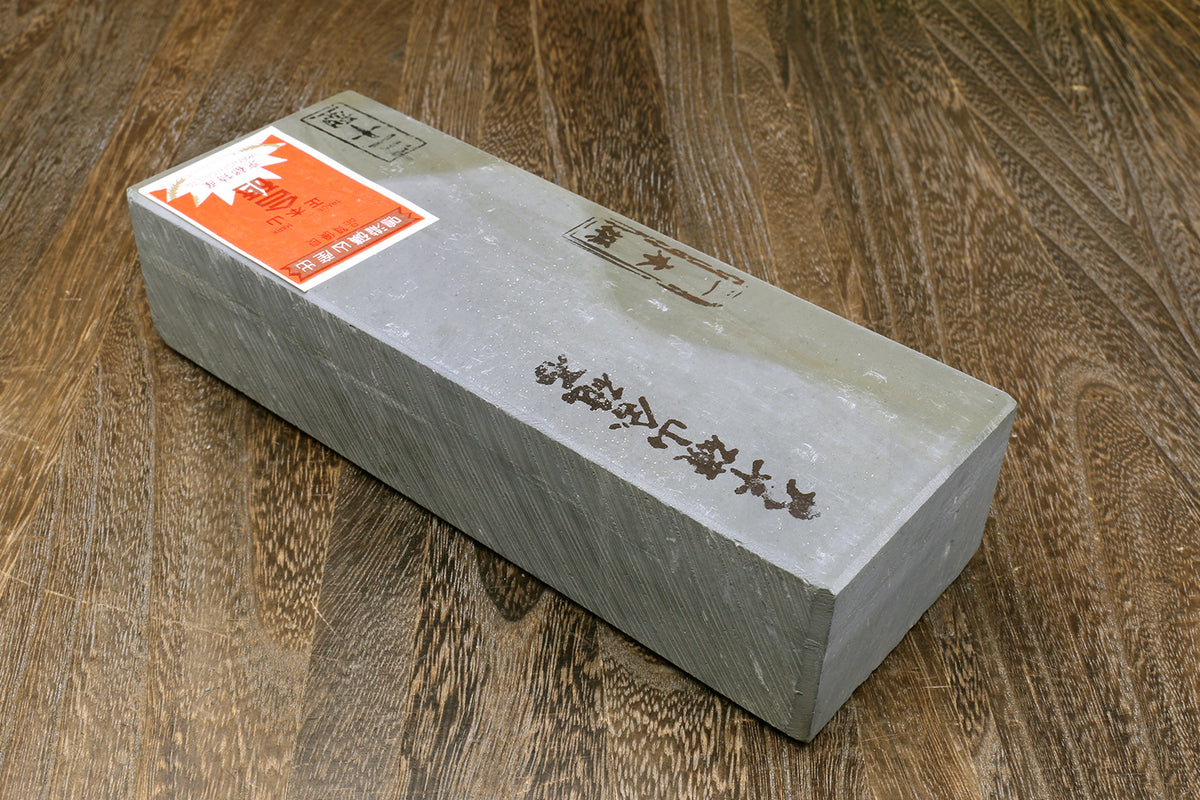 Natural sharpening whetstone block with printed markings and orange label