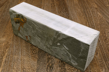 Natural sharpening whetstone, side view of long rectangular gray stone with stamped marks