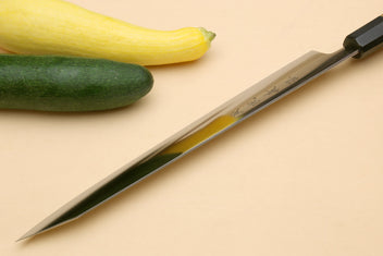 Japanese slicer knife with silver blade and dark black bolster on wood handle