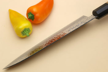 Damascus blade close-up with hammered pattern and black bolster on wooden handle