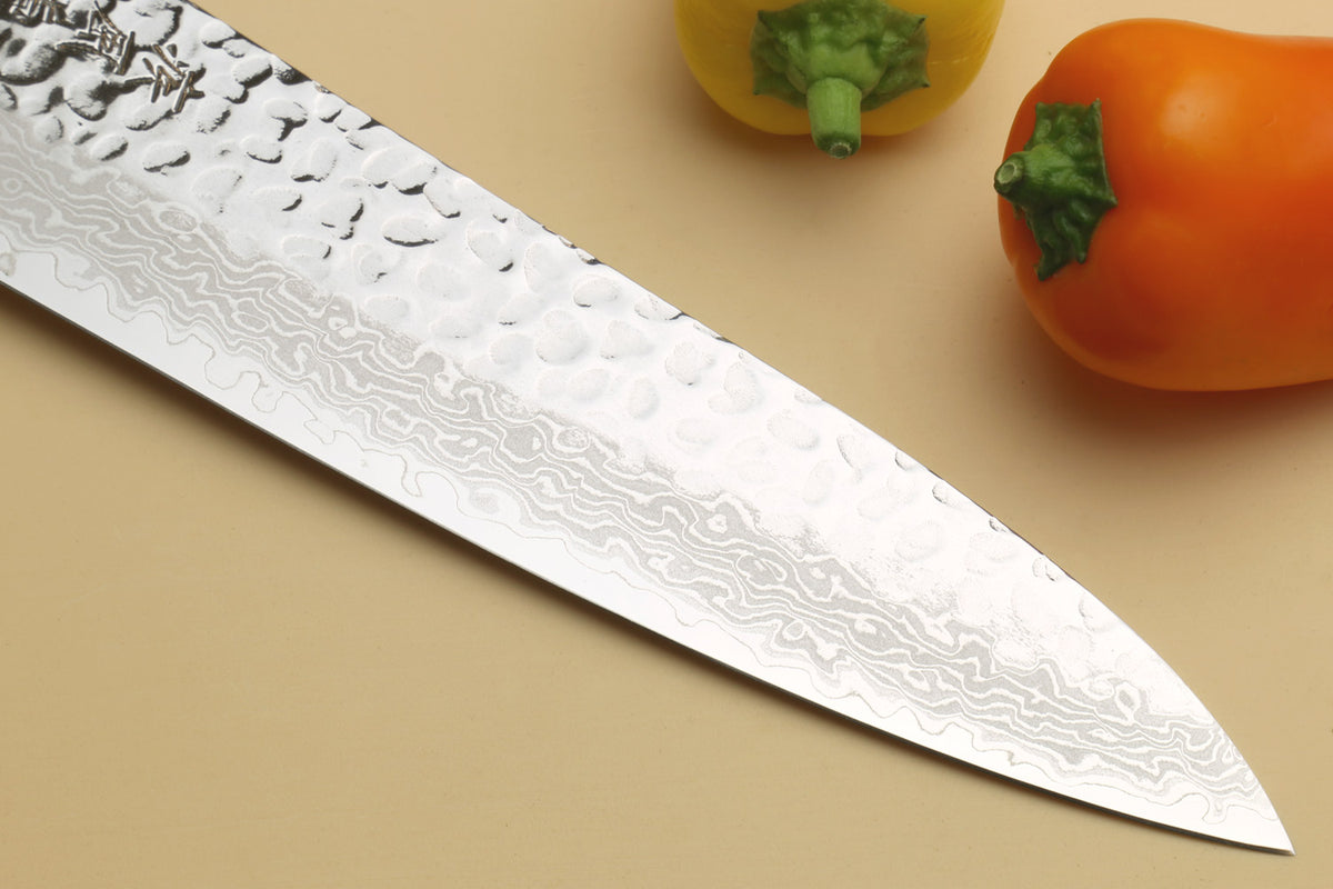 Damascus knife blade close-up with hammered wavy pattern and sharp tip