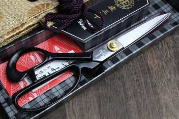 Fabric scissors with black handles, purple bow details, and silver blades