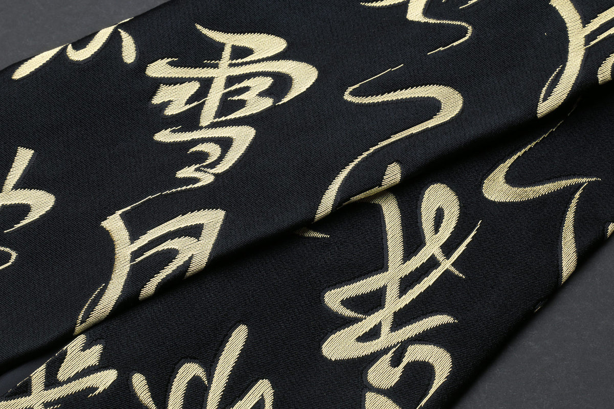 Black Japanese knife pouch bag with gold kanji calligraphy pattern, close-up