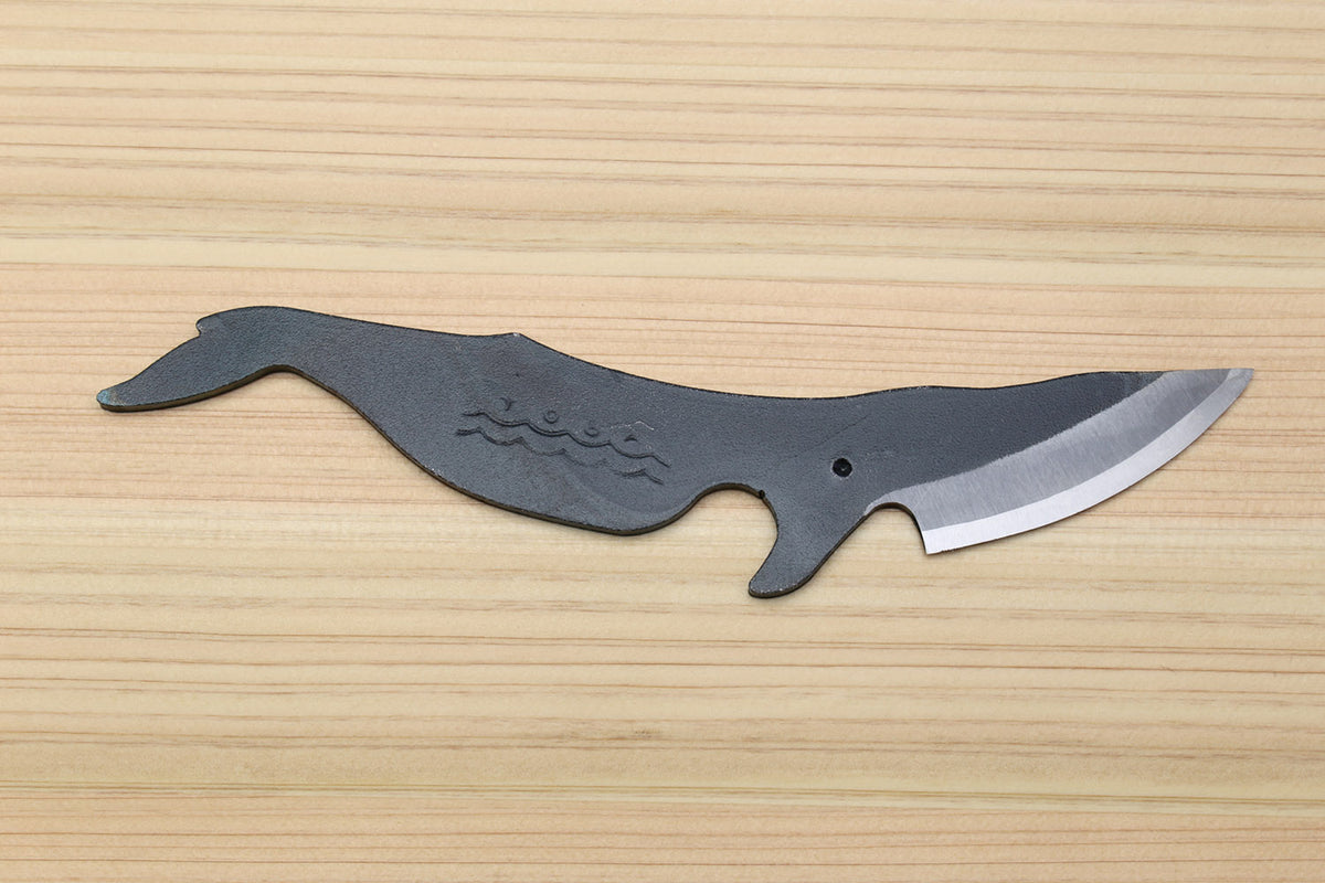 Whale-shaped Japanese utility knife with wavy handle pattern and dark kurouchi blade