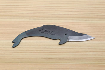Whale-shaped Japanese utility knife with wavy handle engraving and dark kurouchi blade