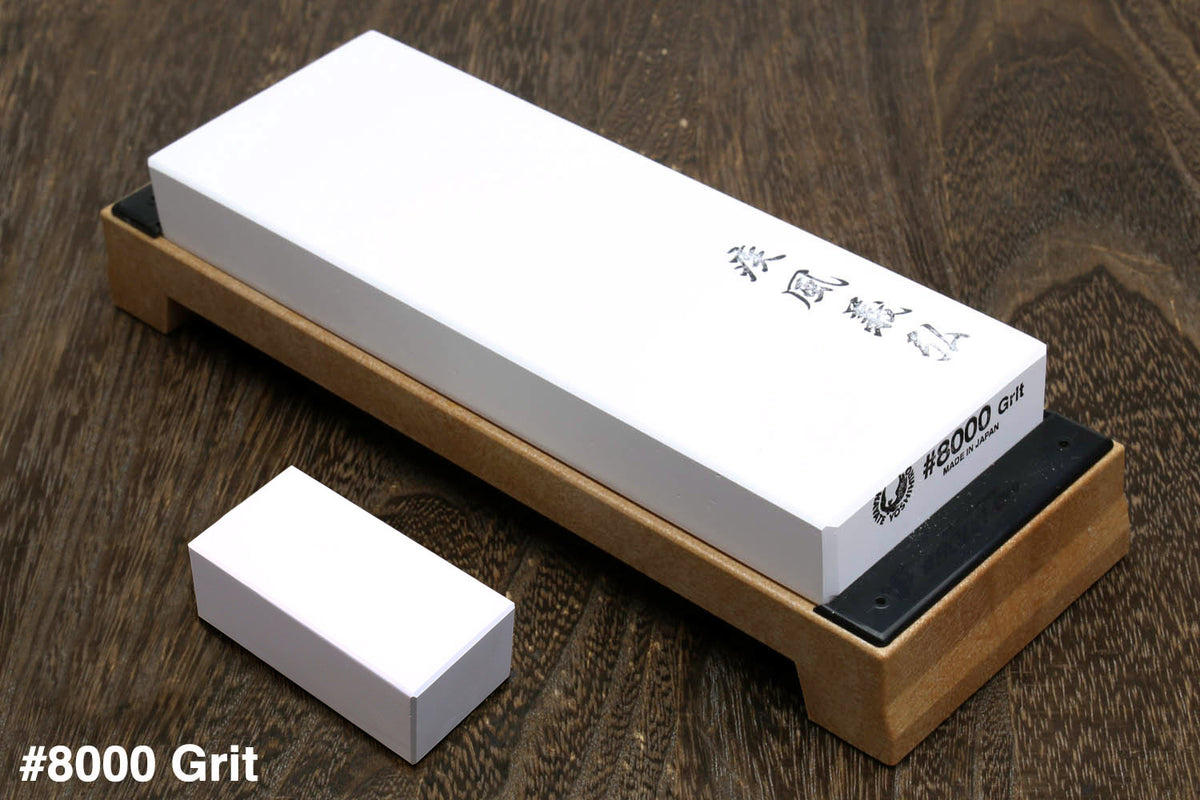 8000-grit sharpening whetstone on wooden base, white stone with dark label edge