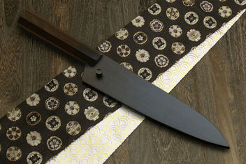 Petty utility knife with dark shitan wood handle and kurouchi blade on patterned cloth