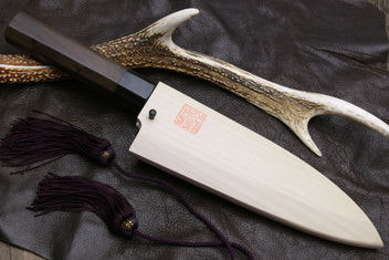 Deba knife with white blade, dark handle, and horn-style decorative guard