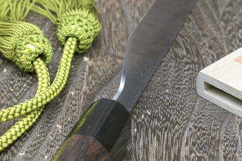 Japanese single-edged vegetable knife with dark wood handle and green tassel cord
