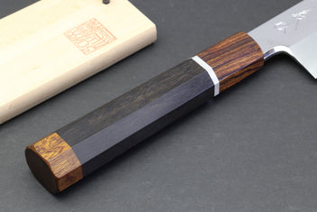 Japanese chef knife with mirror-polished blade and dark handle, wooden sheath nearby