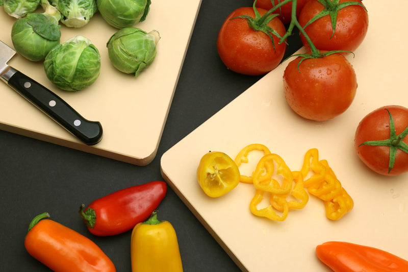 Cream cutting board with vegetables and pepper knife on top surface