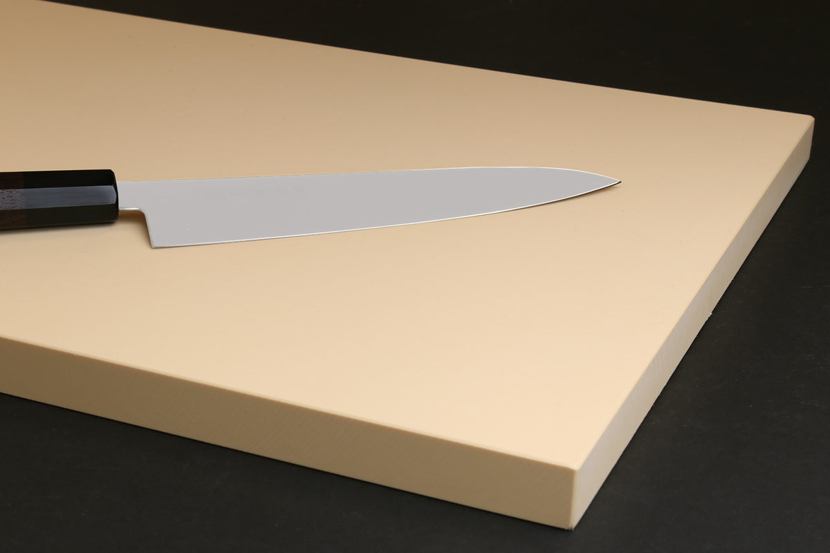Beige cutting board with a chef’s knife resting along the edge, flat smooth top