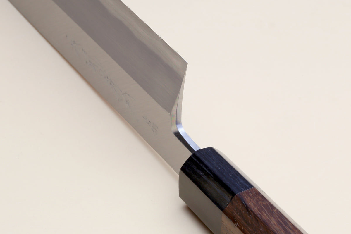 Traditional Japanese vegetable knife with blue steel blade and rosewood handle, angled close-up